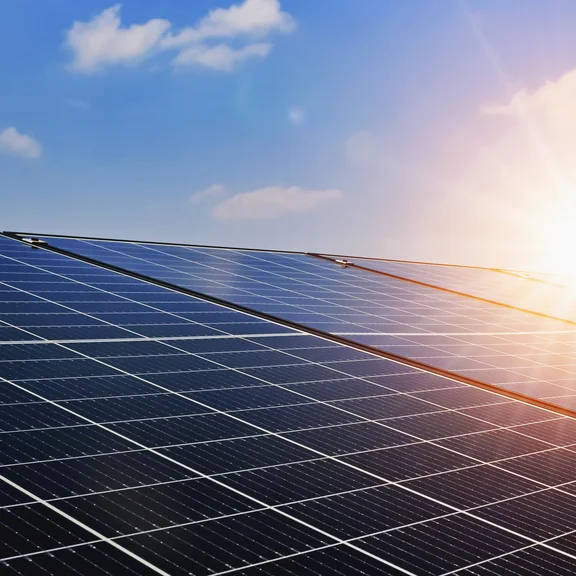 Solarpanels Solarmodule sind vor einem blauen Himmel mit Sonnenschein abgebildet.