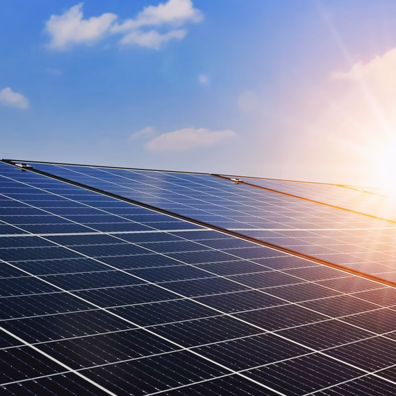 Solarmodule sind vor einem blauen Himmel mit Sonnenschein abgebildet.
