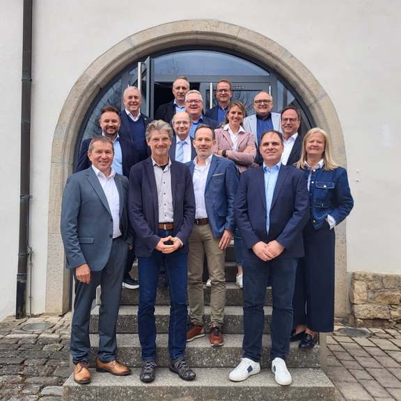 Regionalbeirat Mehrere Personen stehen in Gruppenanordnung auf einer Steintreppe vor einem Gebäude mit Rundbogen-Eingang und Glastür, aufgenommen bei einem Treffen des Regionalbeirats.