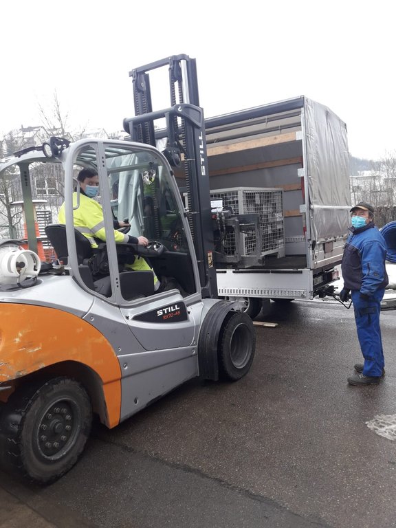 Miarbeiter sitzt auf Stapler und lädt Gitterbox mit Zählern in LKW