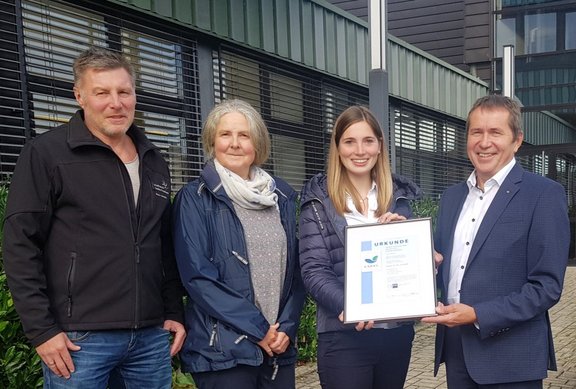 Verantwortliche halten Urkunde in der Hand.