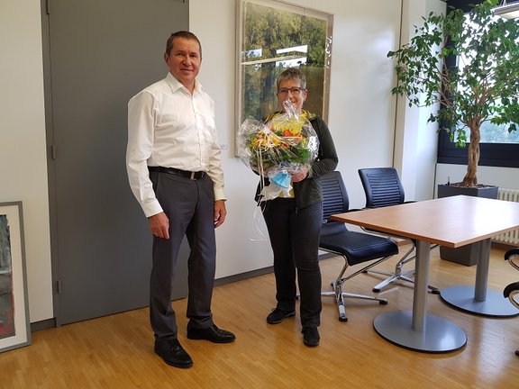 Mitarbeiterin erhält Blumenstrauß von Geschäftsführer