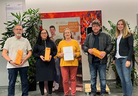 Mitarbeiterin übergibt 4 kleine Päckchen an 4 Gewinner