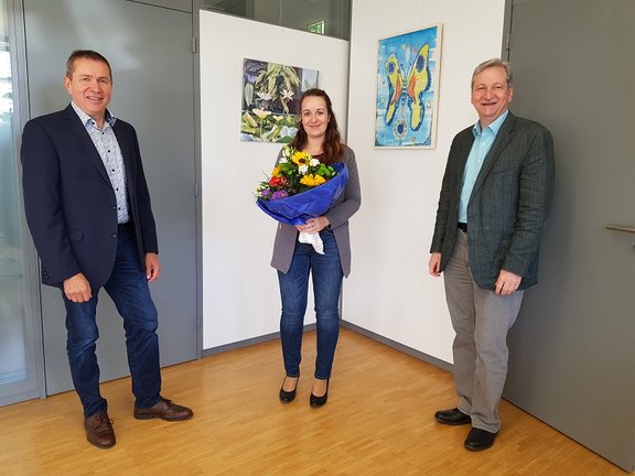 Mitarbeiterin erhält Blumenstrauß von den Geschäftsführern