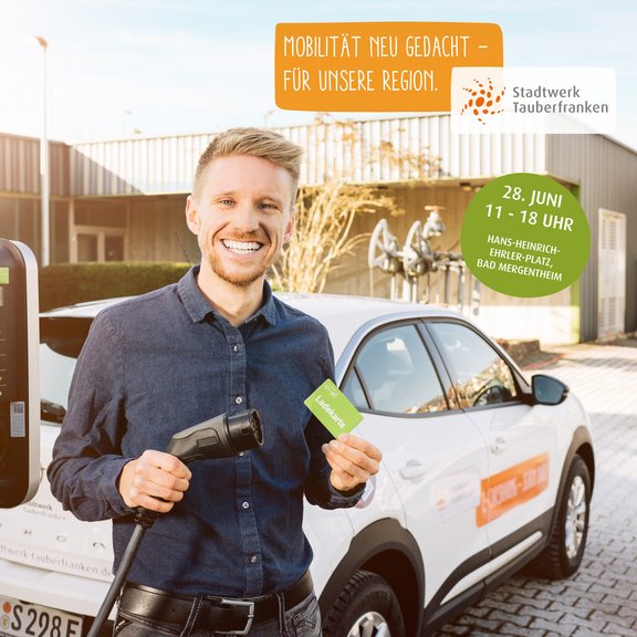 Elektromobilität Person lädt ein Elektroauto an einer Ladesäule und hält eine Ladekarte; daneben Hinweis auf den Regionaltag am 28. Juni (11–18 Uhr) am Hans-Heinrich-Erler-Platz in Bad Mergentheim mit Fokus auf nachhaltige Mobilität