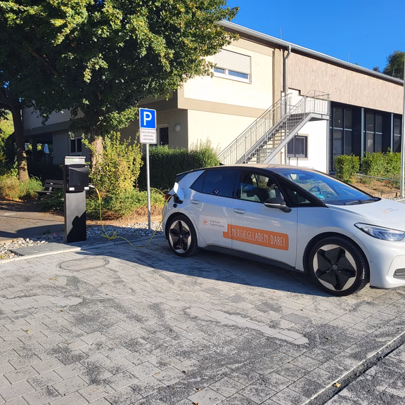 Öffentliche AC-Ladesäule mit zwei Ladepunkten in Althausen. Ein Elektrofahrzeug der Stadtwerk Tauberfranken lädt auf dem neu gestalteten Parkplatz.