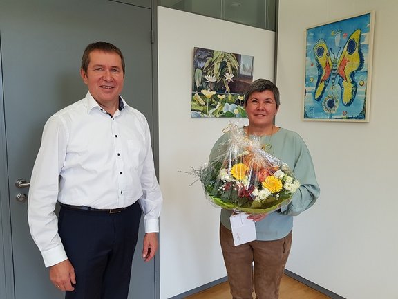 Mitarbeiterin erhält Blumenstrauß von Geschäftsführer