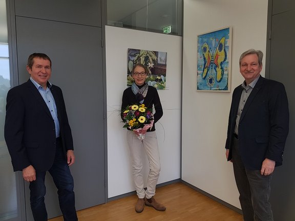 Ehrung Kuhn Mitarbeiterin erhält Blumenstrauß von beiden Geschäftsführern