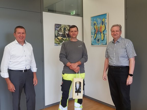 Mitarbeiter erhält Weingebinde von den Geschäftsführern