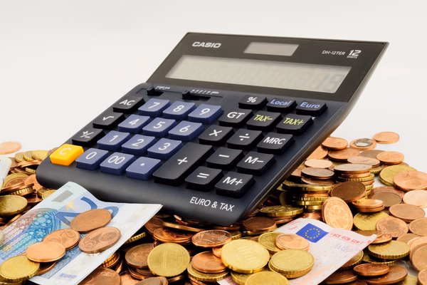 Taschenrechner Förderung Taschenrechner mit der Aufschrift „EURO & TAX“ liegt auf einem Haufen aus Euro-Münzen und -Scheinen, symbolisch für Finanzen, Steuern oder Kostenberechnung.