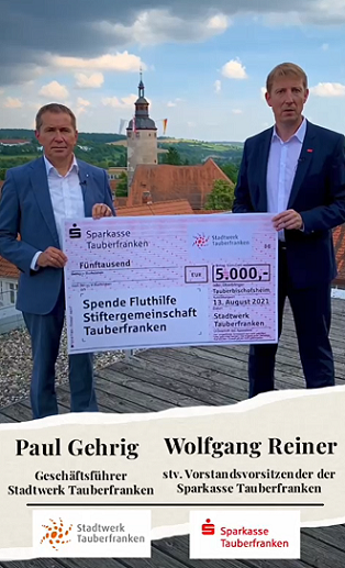 Stadtwerk-und Sparkassenvertreter halten einen 5.000 € Spendencheck in der Hand und stehen auf einer Dachterrasse